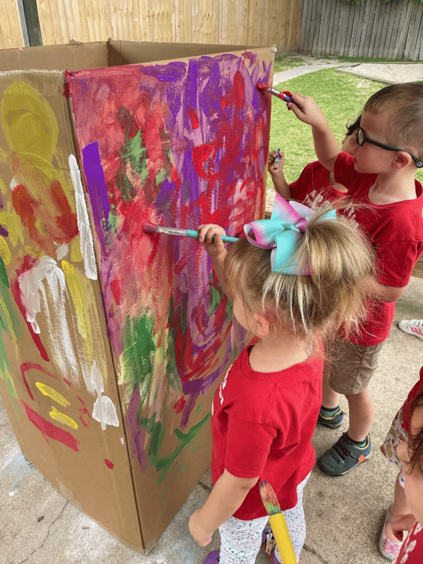 Students painting on cardboard box